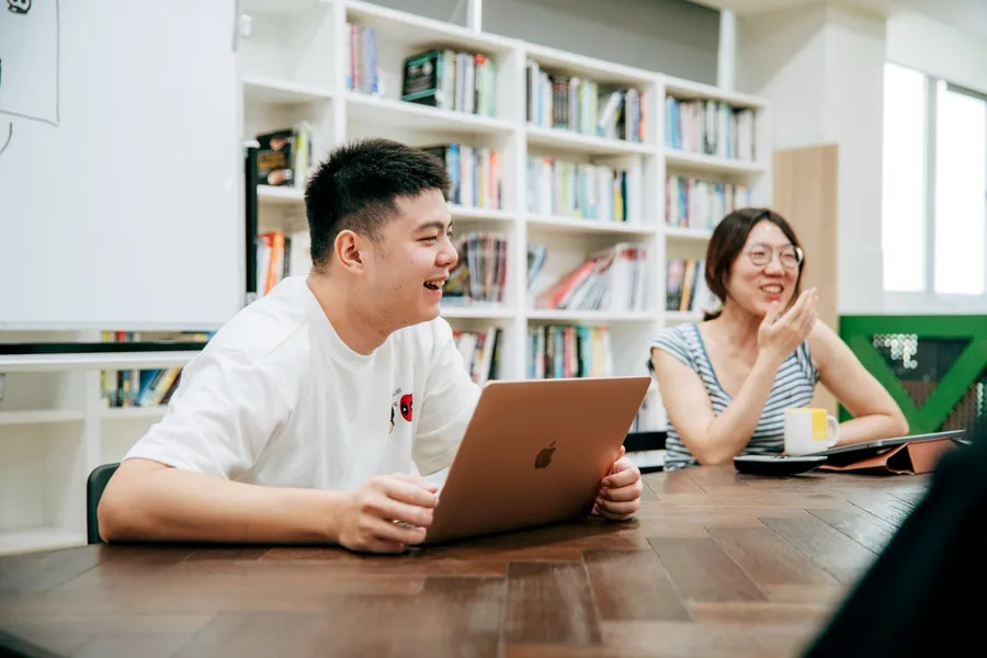 兩個人在會議桌前笑著討論
